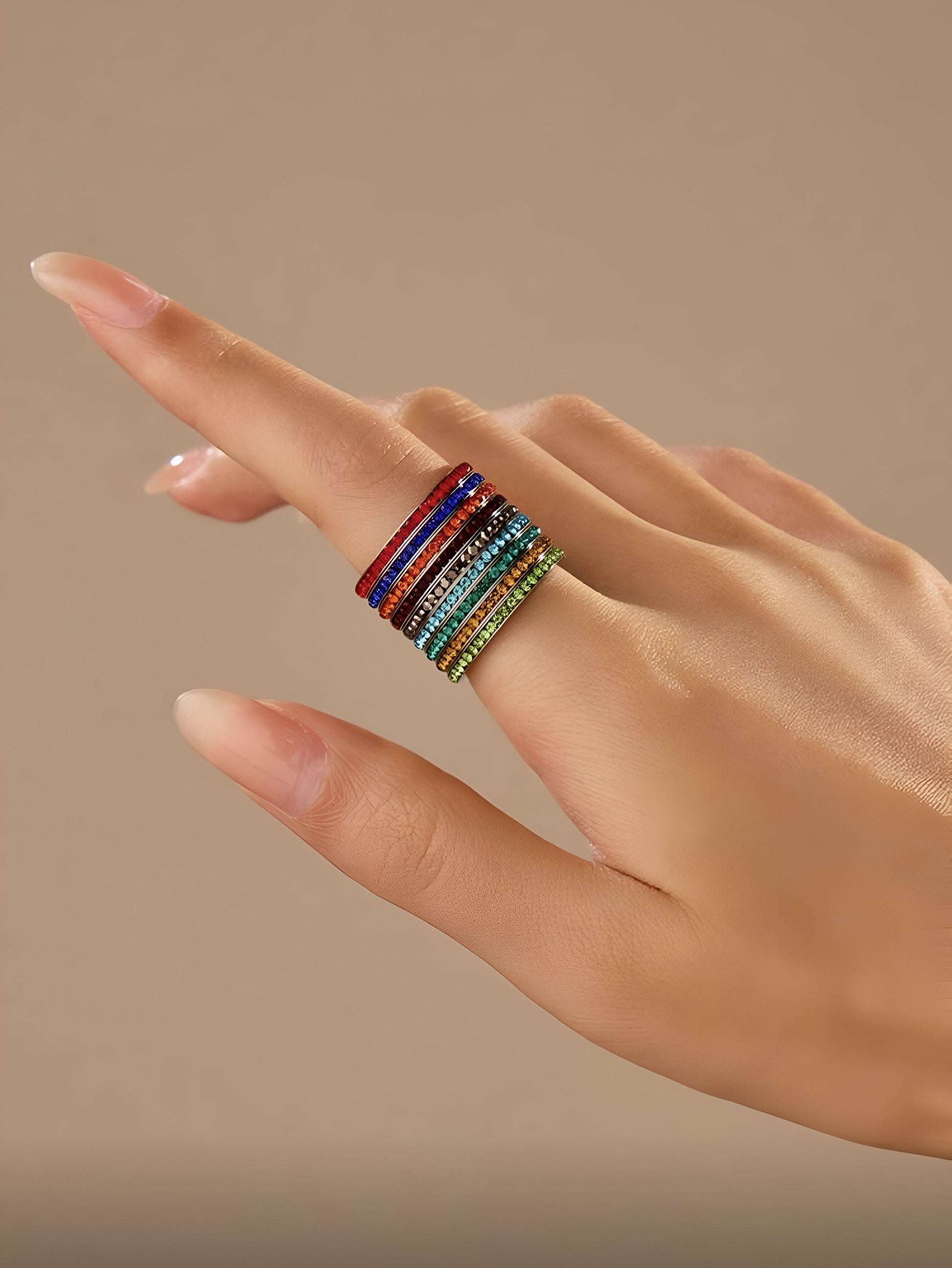 9-piece rainbow stacking rings set in vibrant colors on a soft beige background, minimalist modern jewelry, HAVA Store aesthetic