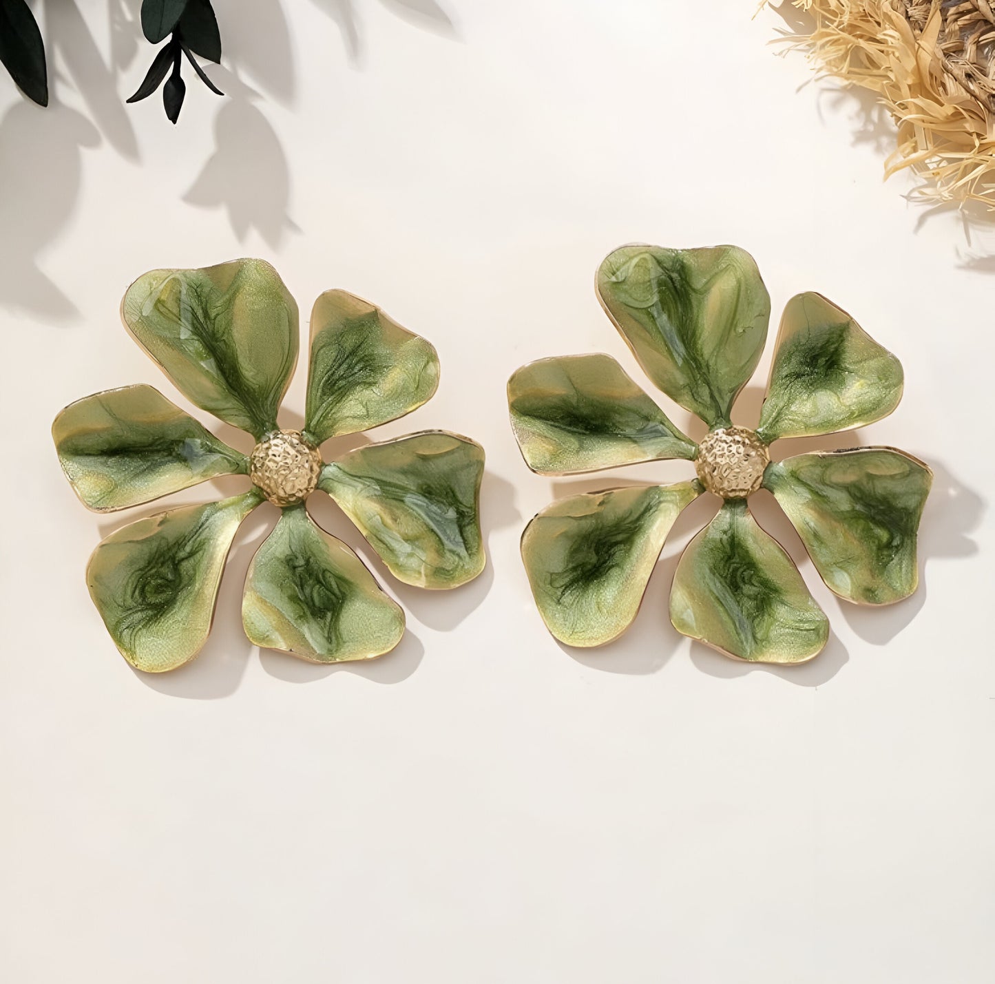 Close-up of green metal flower earrings with enamel petals.